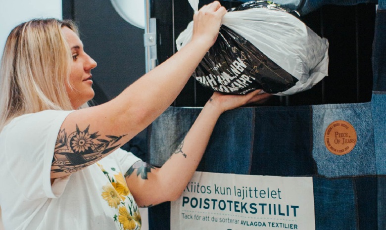 A woman puts a plastic bag into HSY’s free-of-charge end-of-life textile collection point.