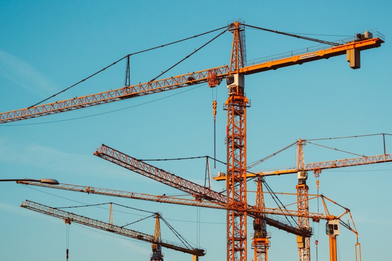 Several tower cranes in front of blue skies.