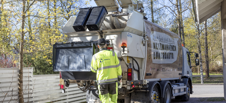 HSY:n jäteautoon tyhjennetään monilokeroastiaa. Mies seuraa vieressä.