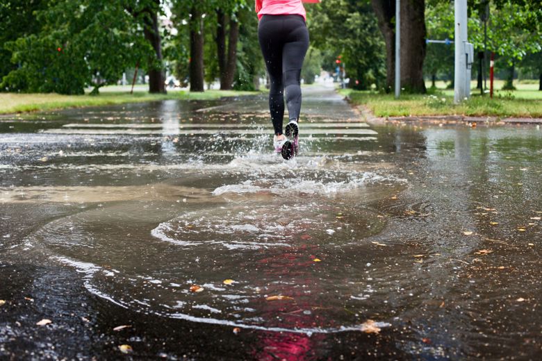 Woman runs across a pedestrian crossing, which is covered with puddles. Picture: HSY. Photographer: Suvi-Tuuli Kankaanpää.