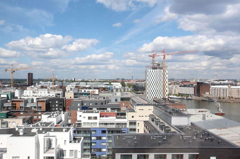 Densely-constructed new city area from the roof level. Cranes can be seen here and there. White clouds against the blue sky.